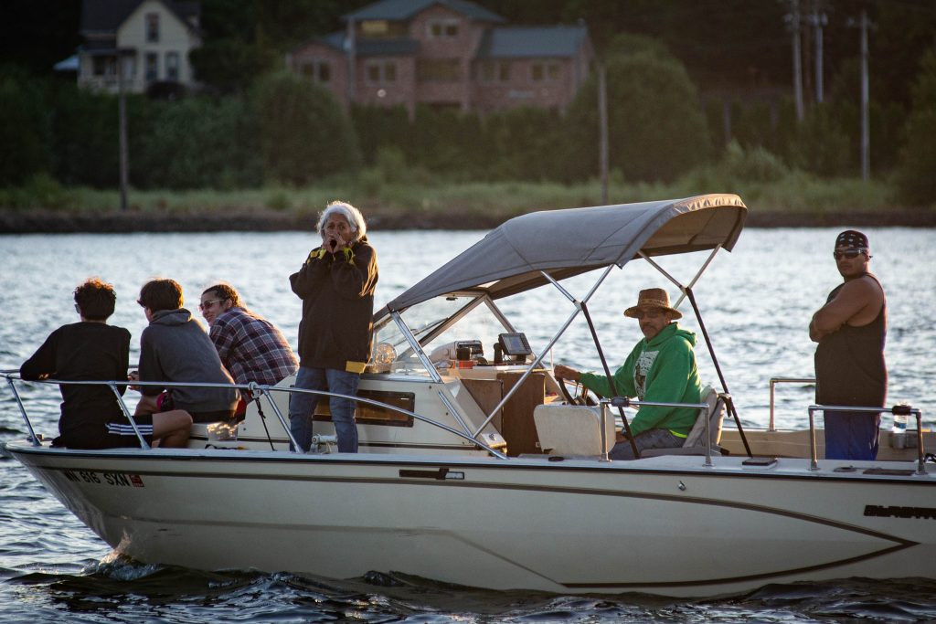 People in a modern boat watching the Squaxin Island Tribal members in canoes on the puget sound