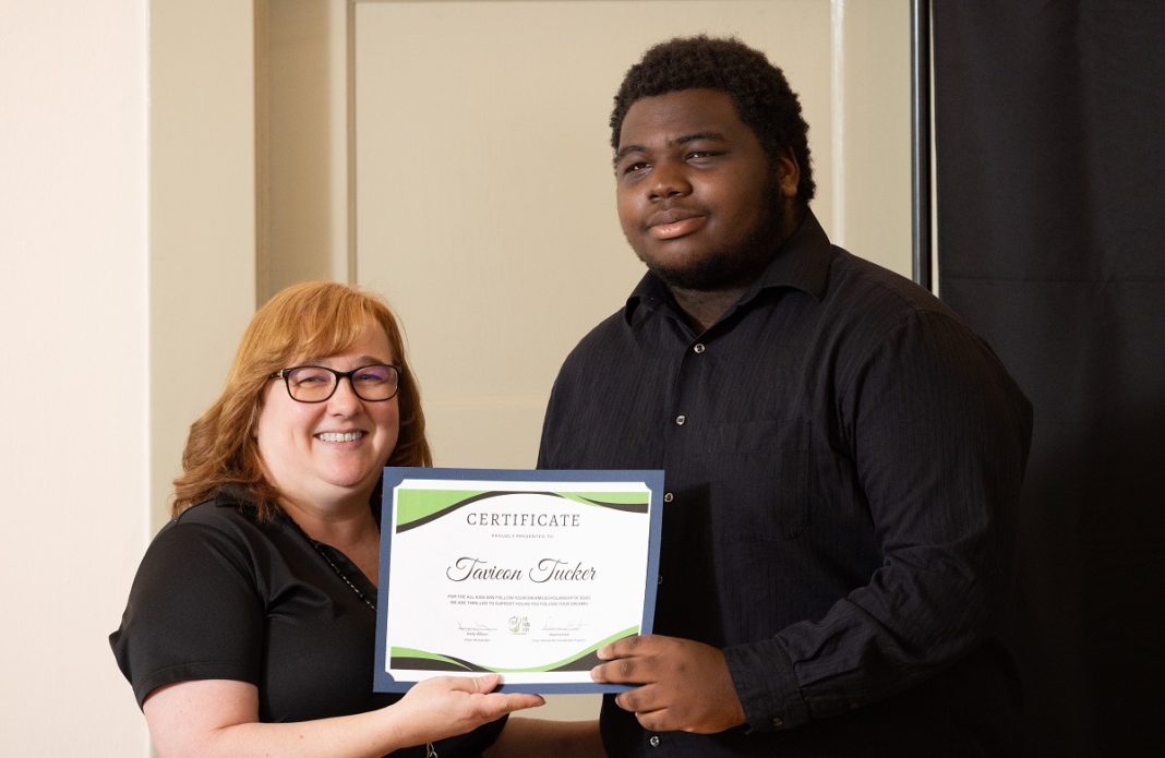 A man stands next to a woman, each holding a side of the certificate