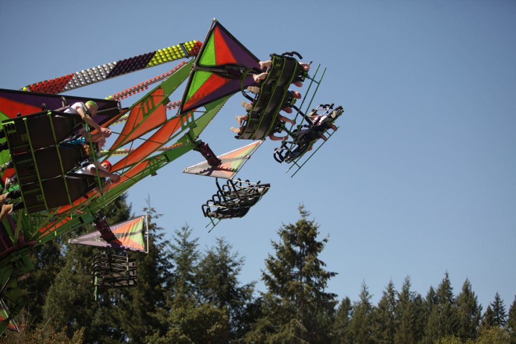 a swinging carnival ride with a treeline in the background