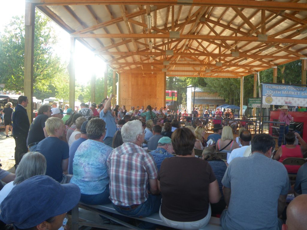 a large group of people sit on benches in a covered outdoor seating area