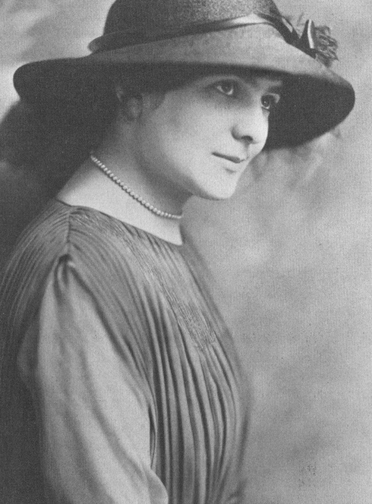 black and white photo of a woman in a black hat and simple dress