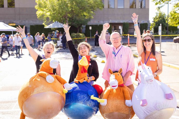 for people hold up plush bouncing ride on toys, two horses, a rooster and a unicorn