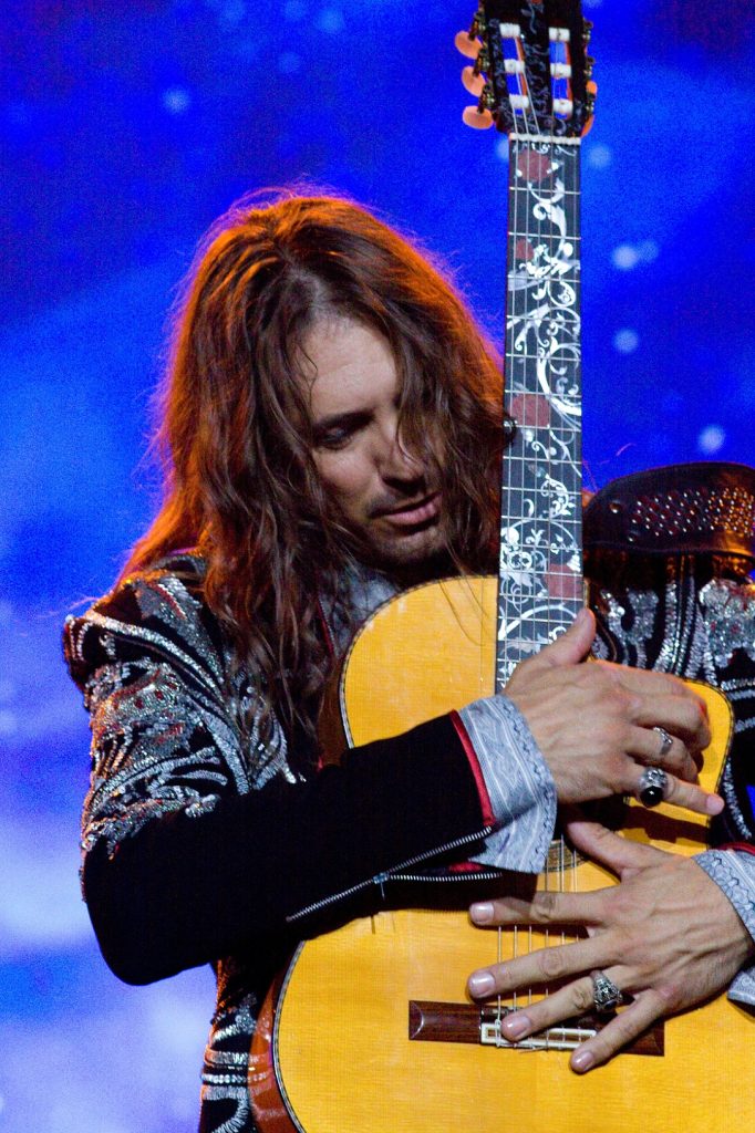 Close up of Benise on stage holding a guitar vertically while playing it