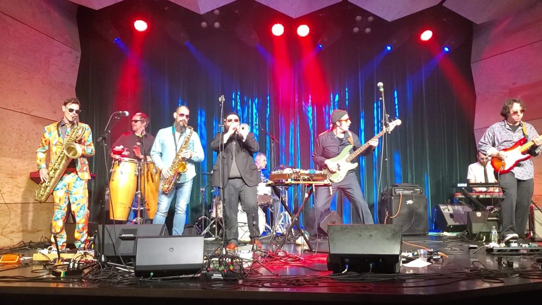 Large band performing on stage under red lights