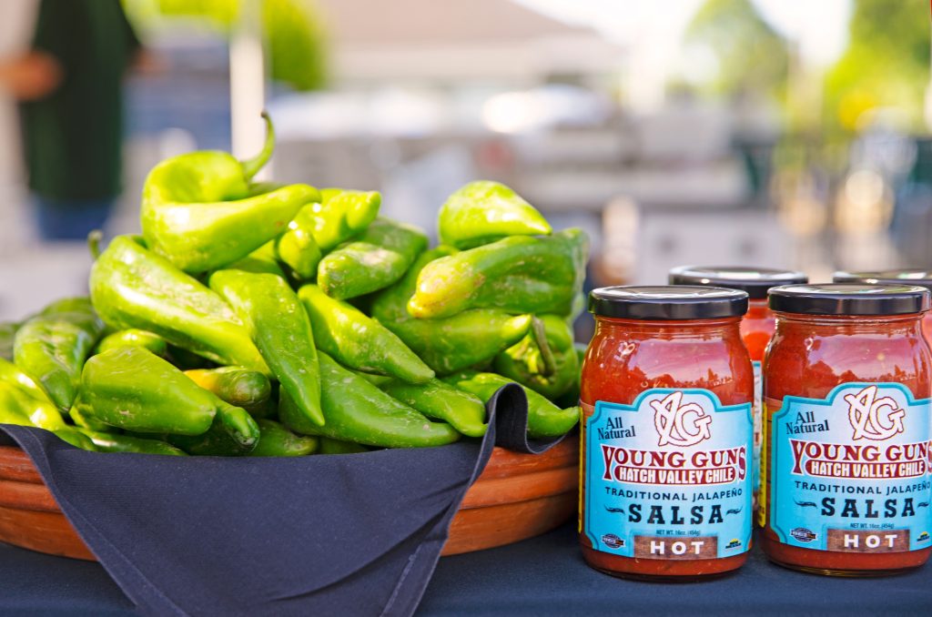 large bowl of green chilies next to a jar of salsa