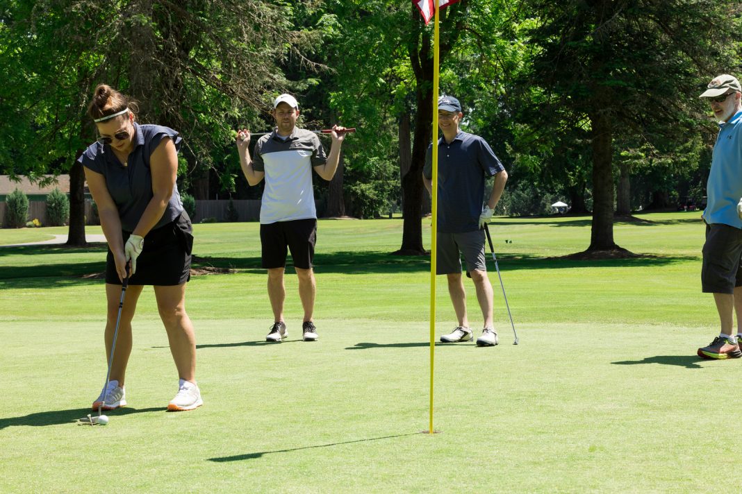 three people on a golf course playing golf