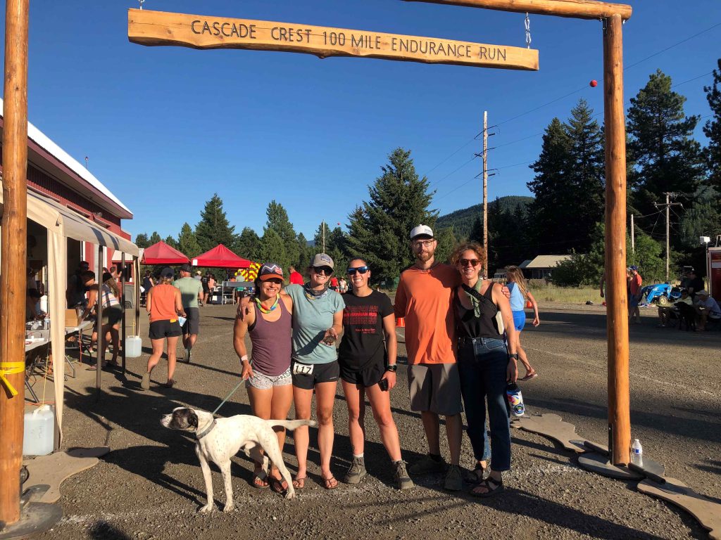 five people with a dog pose for a photo at the Cascade Crest 100 finish line. 