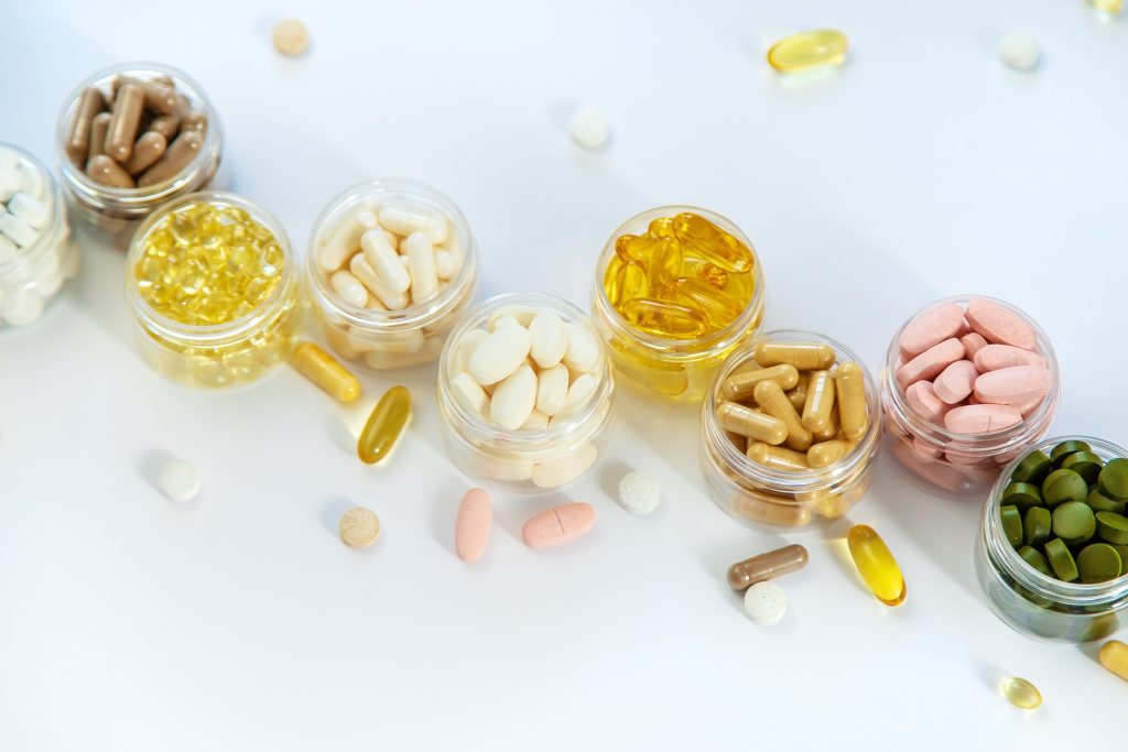 a line of bottles off of different colored pills photographed from above on a white background