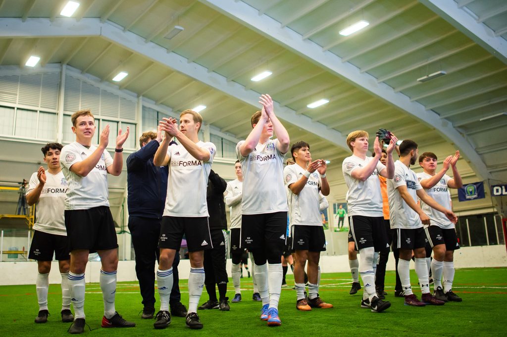 Older kids stand in soccer outfits clapping hands