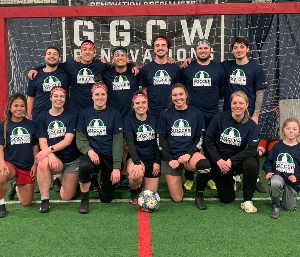 Indoor soccer co-ed team photo with a goal behind them.