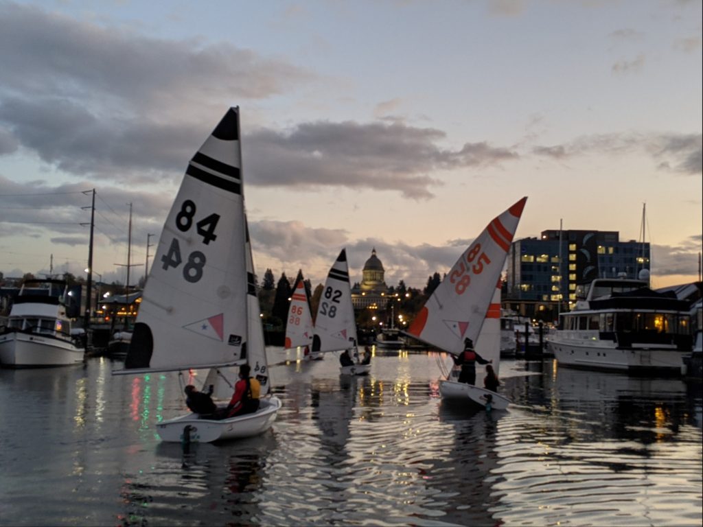 High School Sailing team members sailing back towards the dock at sunset