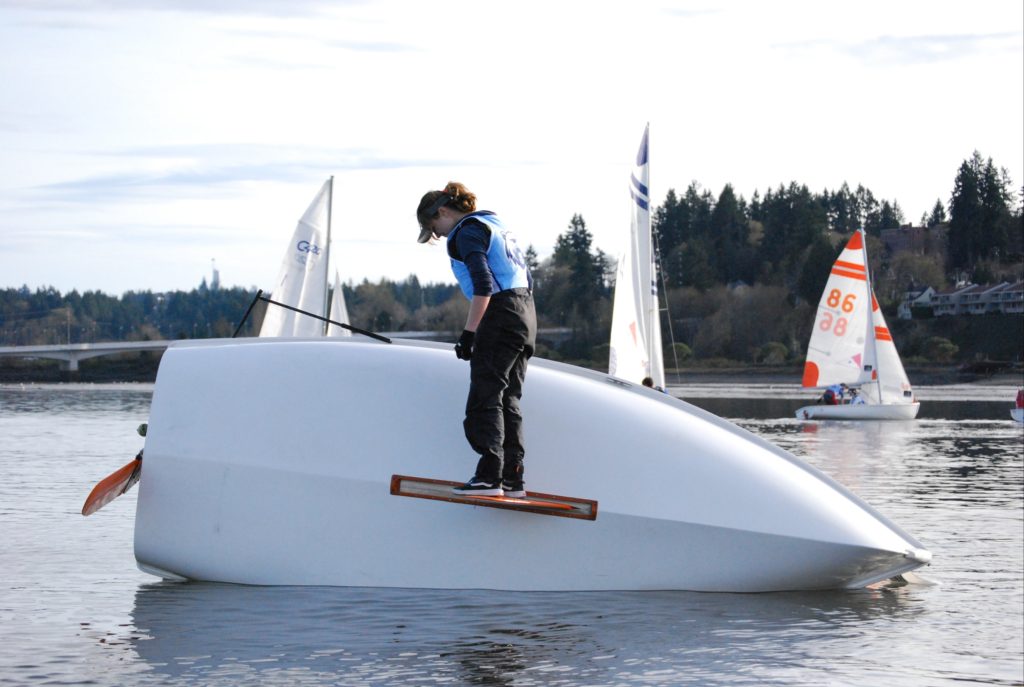 High school student stands on a rudder of a capsized boat