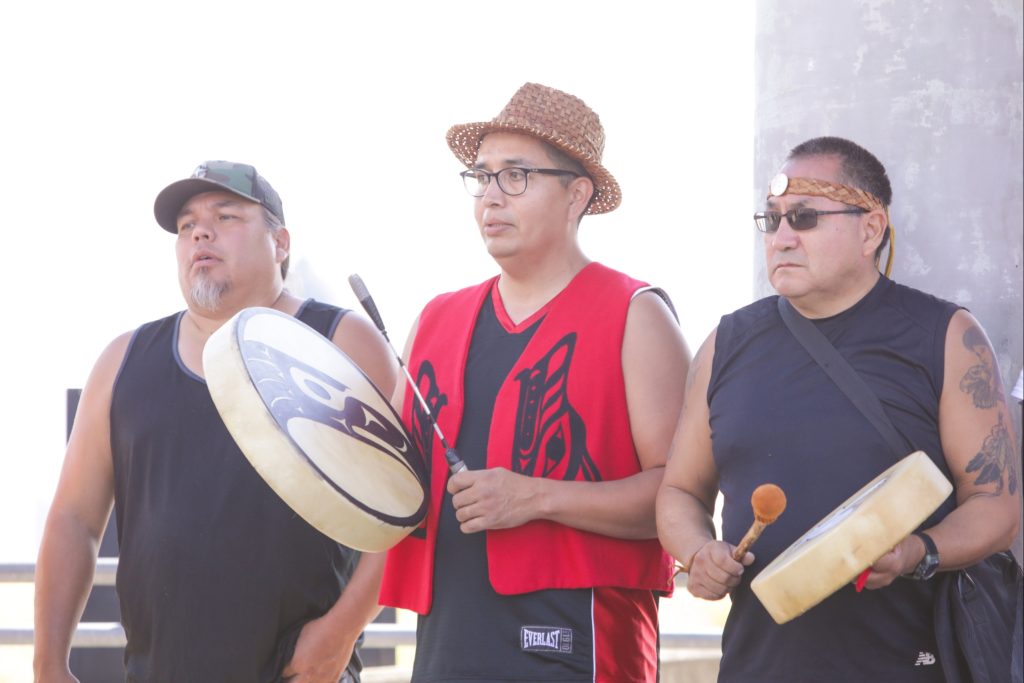 three men playing traditional Native American drums