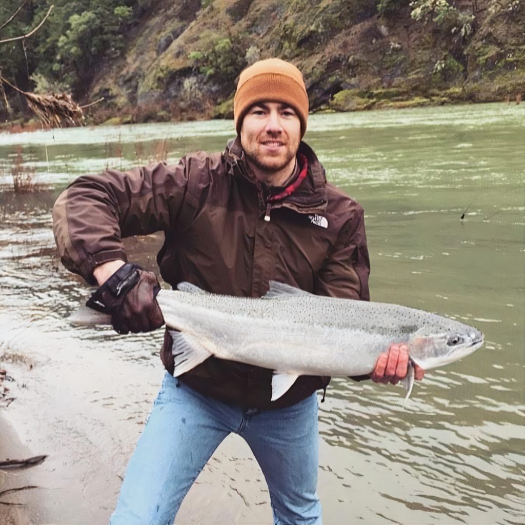 Dr. Ryan Hadden holding a big fish by a river