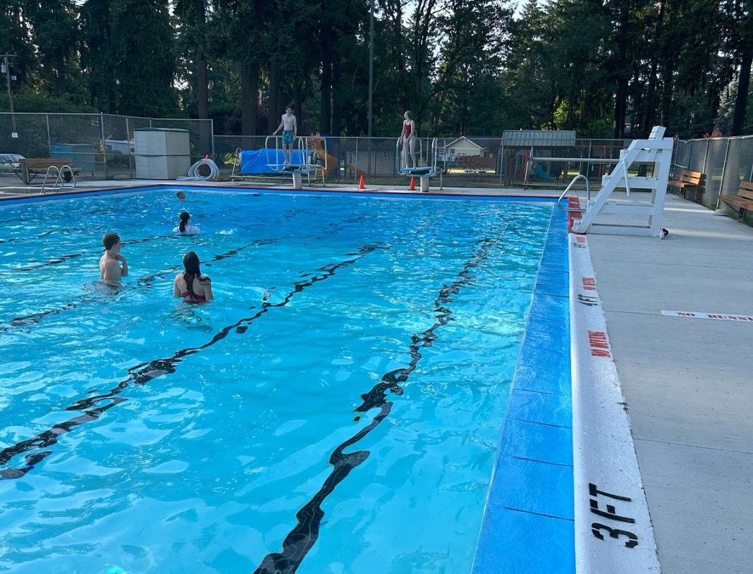 outdoor pool in lacey with lane makers painted on the bottom and three people standing in the shallow end