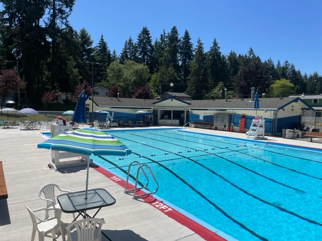 outdoor pool with lane makers painted on the bottom and chairs with umbrellas on the deck