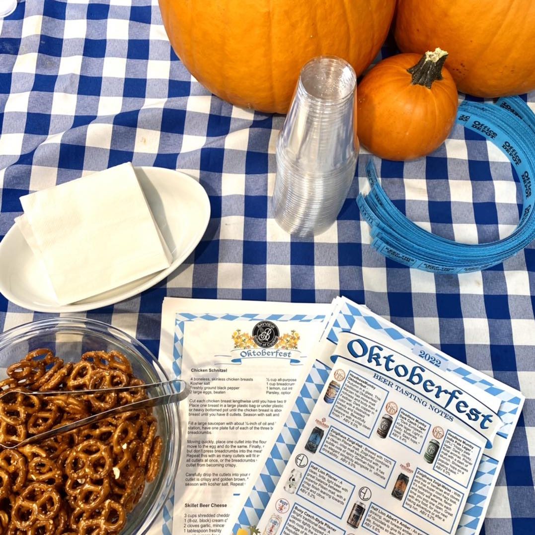 blue and white checked tablecloth with a pumpkin, bowl of pretzels and an Oktoberfest menu on it.