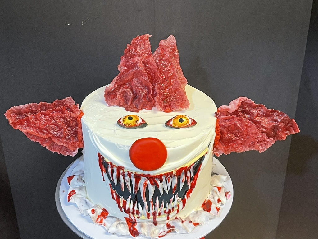 Killer clown cake with red and white frosting, bloody teeth and eye eyes