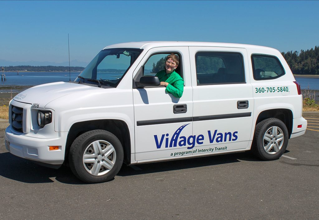 White Intercity Transit Village Van with Ici LeMay in the driver's seat.