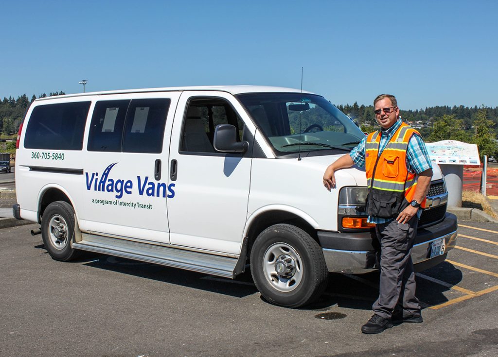 Terry Swartos standing with his arm across the hood of a Intercity Transit Village Van