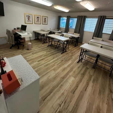 an empty classroom at Olympia School of Advanced Skincare with long white tables and chairs
