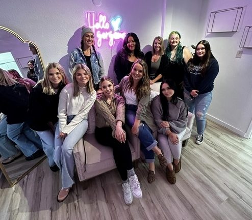 Large group of woman, some sitting and some standing, inside the Olympia School of Advanced Skincare