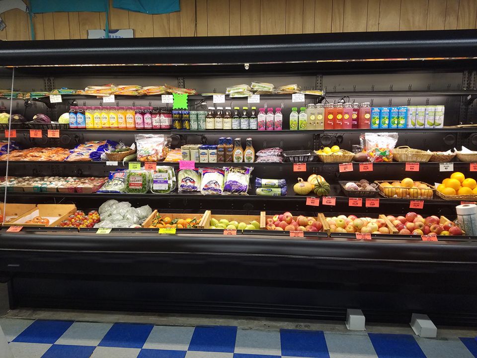 Chilled produce section at  Gull Harbor Mercantile with various fruits, vegetables and bottled juices on shelves.
