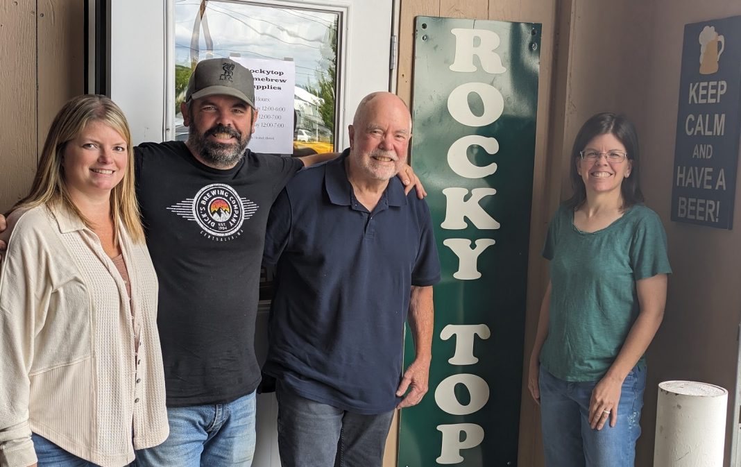 four people smiling for the camera with the a sign that says, 'Rocky Top" in vertical letters