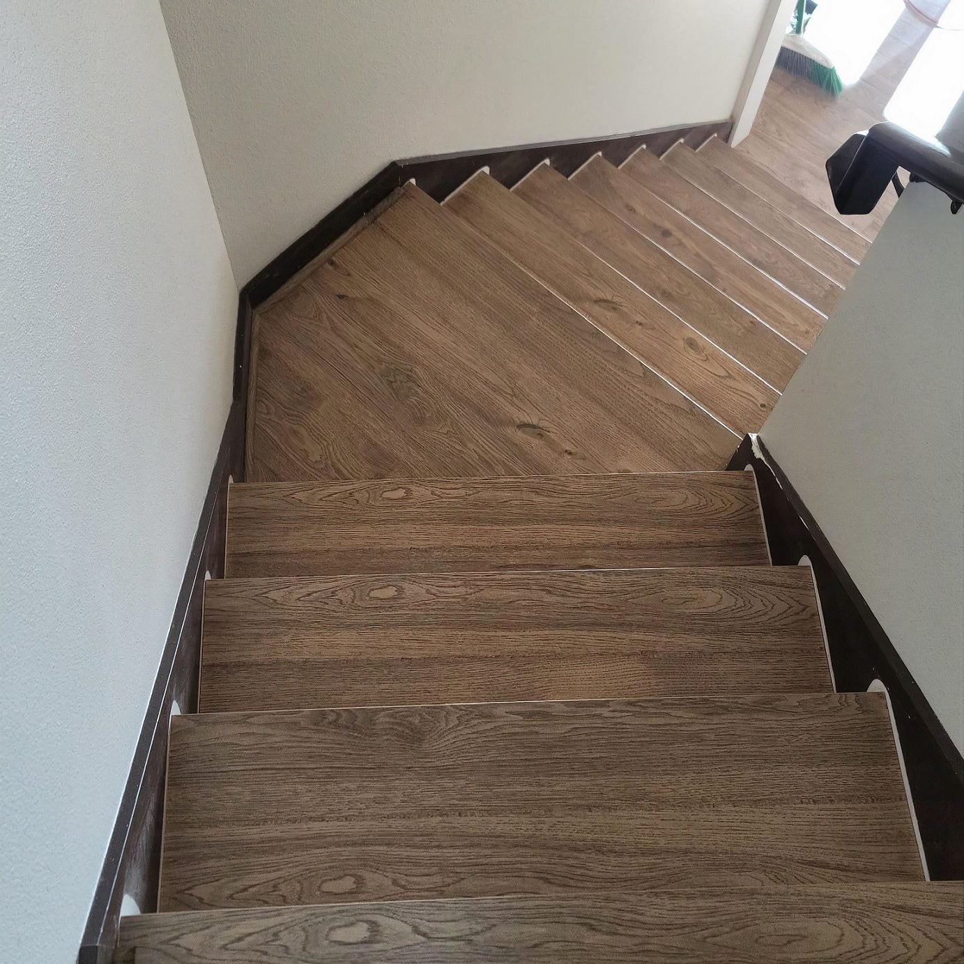 view from the top of stairs in a home with laminate hardwood-look flooring