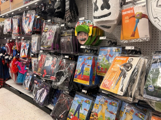 an aisle full of Halloween costumes in plastic bags on hooks.