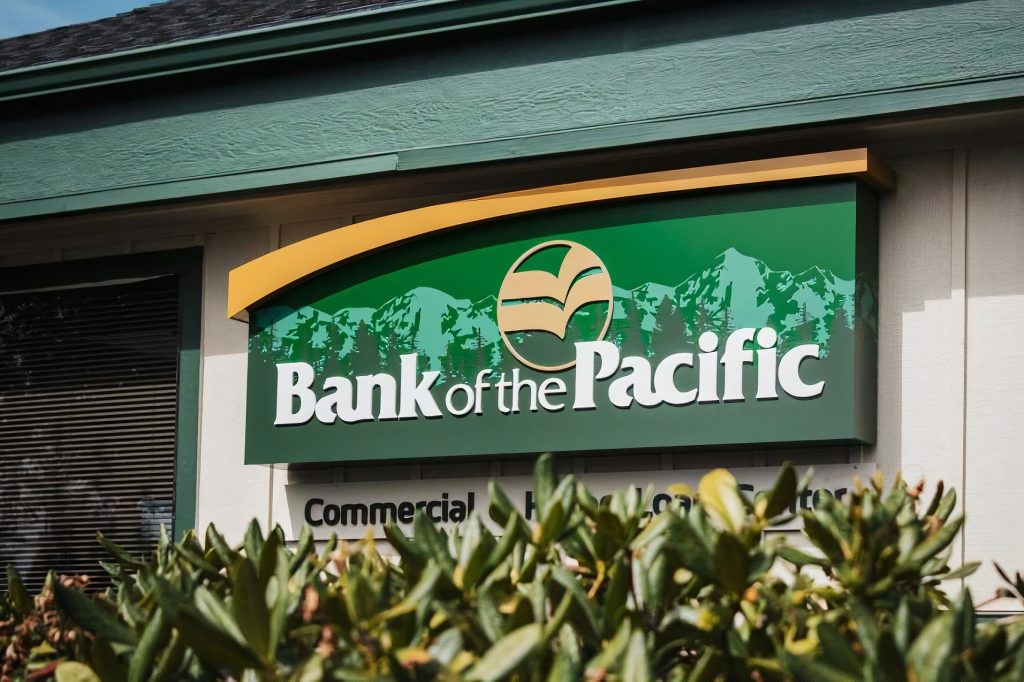close up of the Bank of the Pacific wood sign by some shrubs