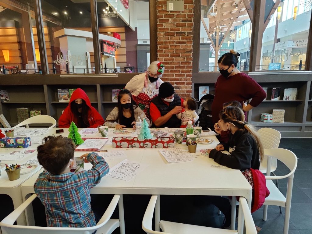 Kids at a large white table making Christmas decorations with paper at the Capital Mall