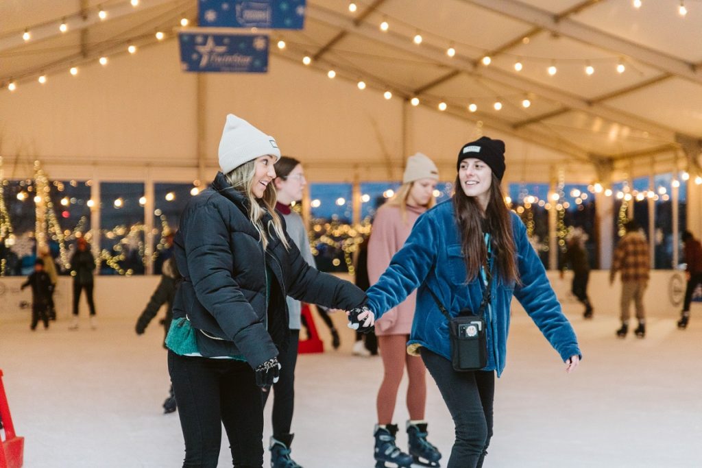 two women hold hands while ice skating in Olympia