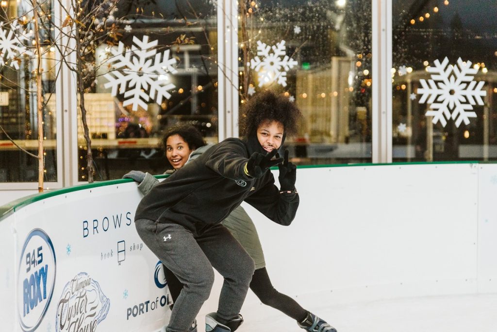 two teens laugh while ice skating in Olympia