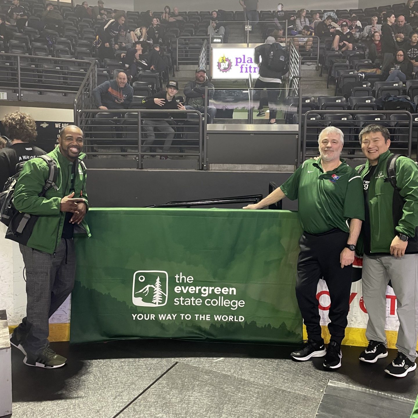 The Evergreen State College banner with coaches and wrestling people next to it