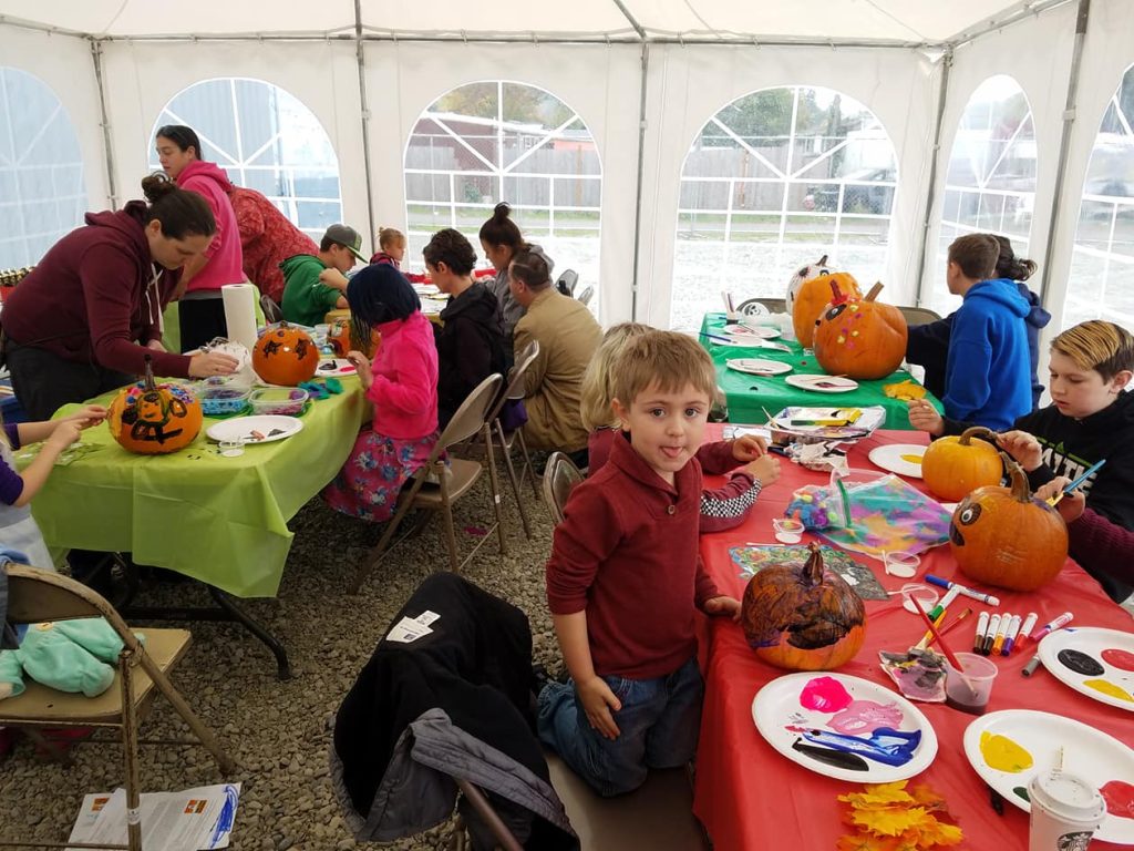 kids at long tables covered with pumpkins, paint and brushes