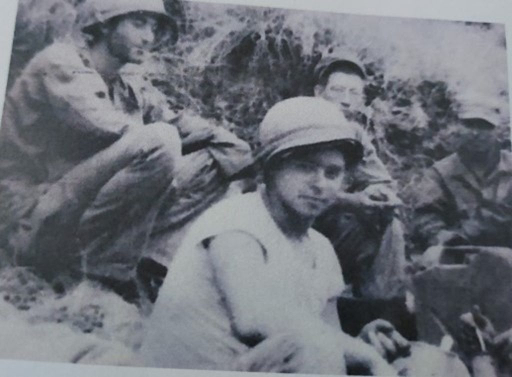 black and white photo of Harvey Drahos during WWII in the field sitting with fellow soldiers