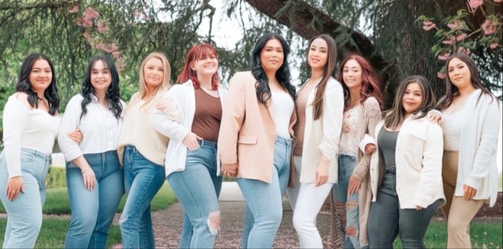 five woman posing for a photo outside with a tree behind them