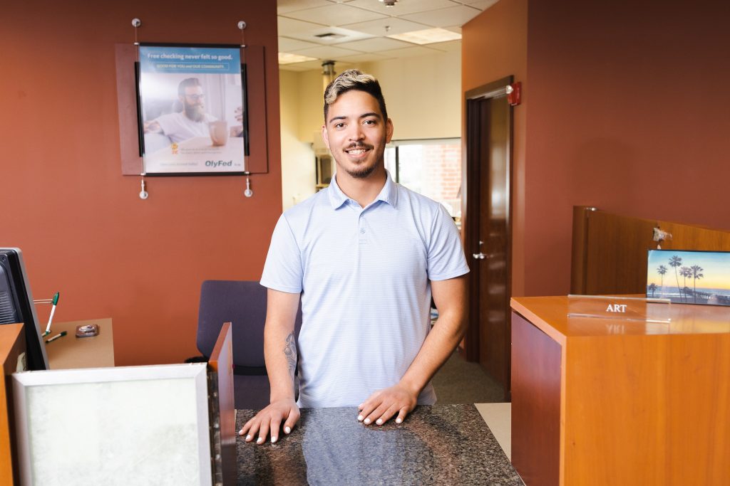 man standing behind the counter at an OlyFed branch