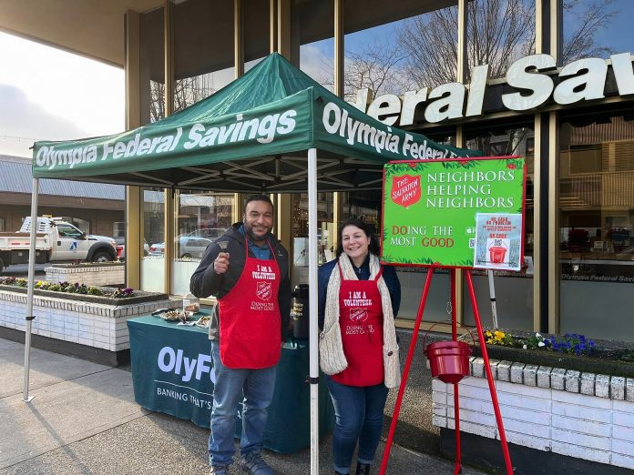 Omar Arcelay ringing bells for Salvation Army under an OlyFed pop-up tent