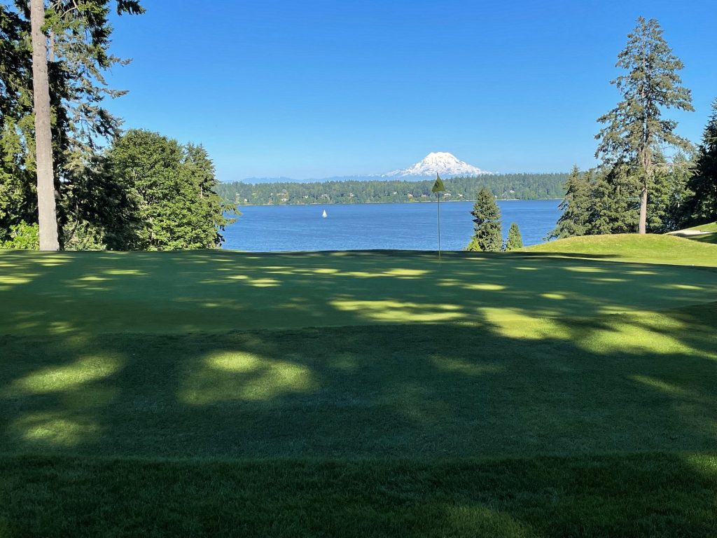 Olympia Country and Golf Club hole with trees, the Puget Sound and Mount Rainier in the background and grass all around