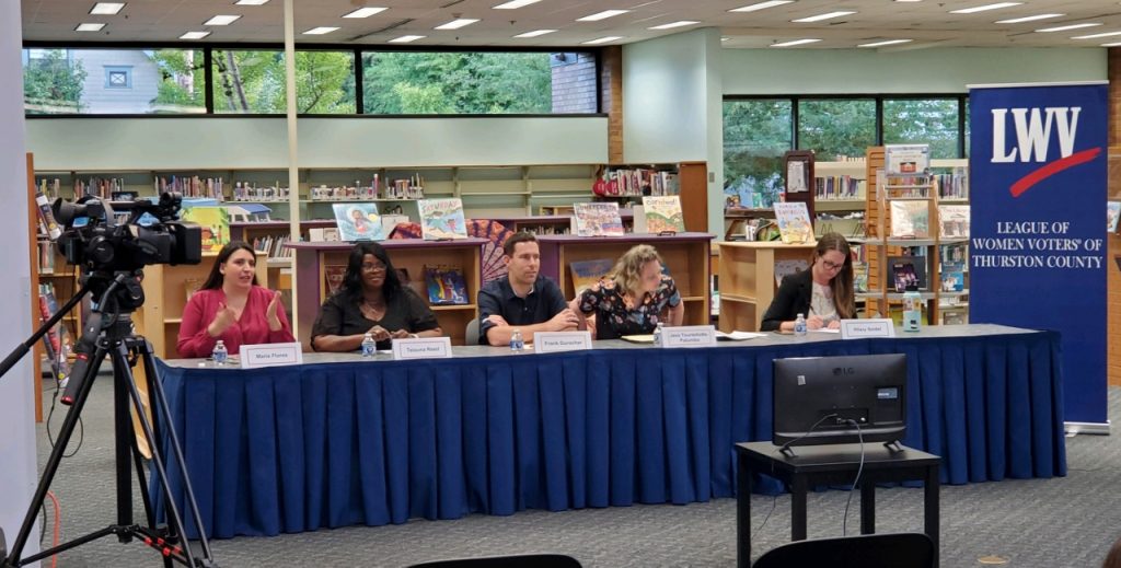 Olympia School Board candidates sitting at a long table at the Timberland Library