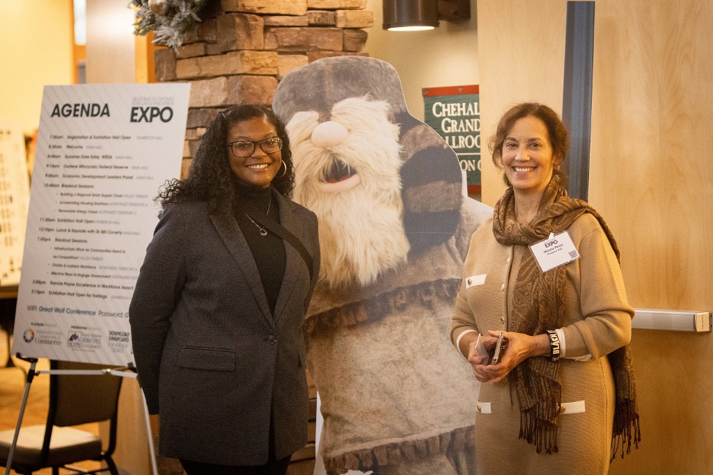 Two people standing next to a cardboard cut out of a bearded character in a coonskin cap and buckskins.