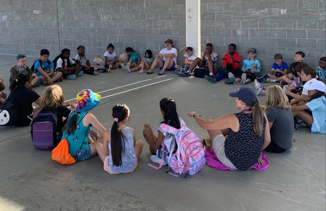 kids sitting in a circle on a concrete play space