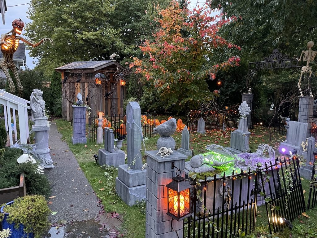 a backyard full of fake skeletons, a fake graveyard, covered bridge and other Halloween decorations