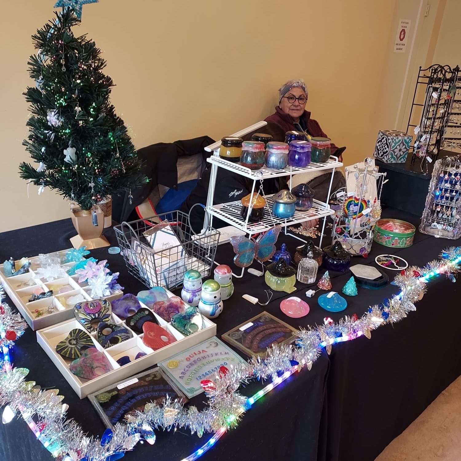 a small Christmas tree, some tinsel garland and an assortment of gift items on a table.