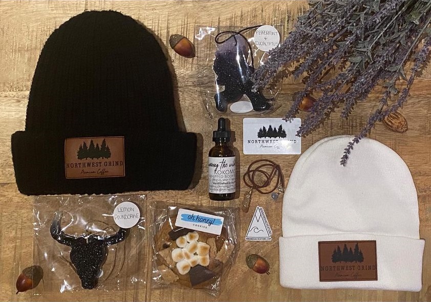 beanies, cookies, giftcards, air fresheners and more on a table, all with the Northwest Grind logo.