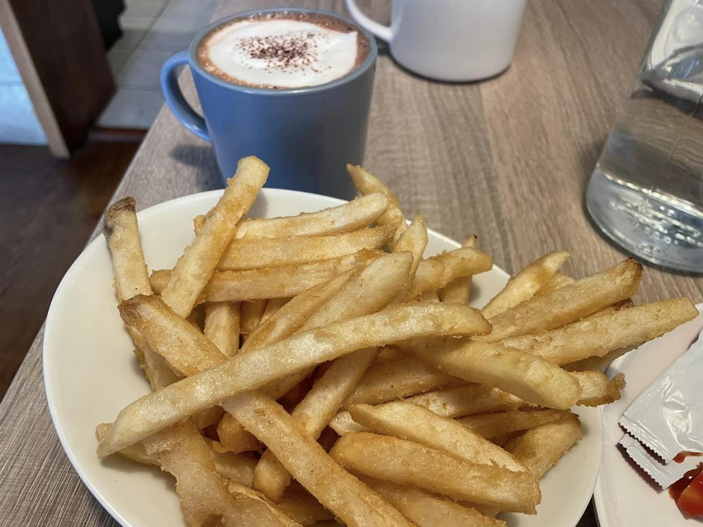 a plate of french fries and hot chocolate with cinnamon on top next to it.