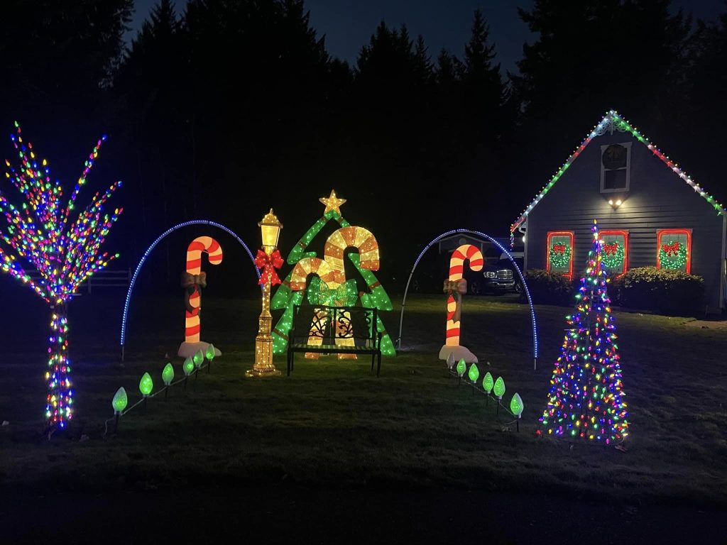 a bench surrounded by large, lit-up candy canes, path markers and a Christmas tree