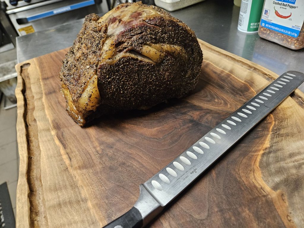 prime rib on a wooden board with a large cutting knife next to it